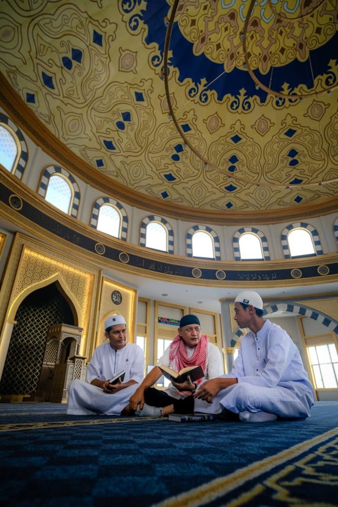 Three young men discuss religious texts under a mosque's ornate dome.